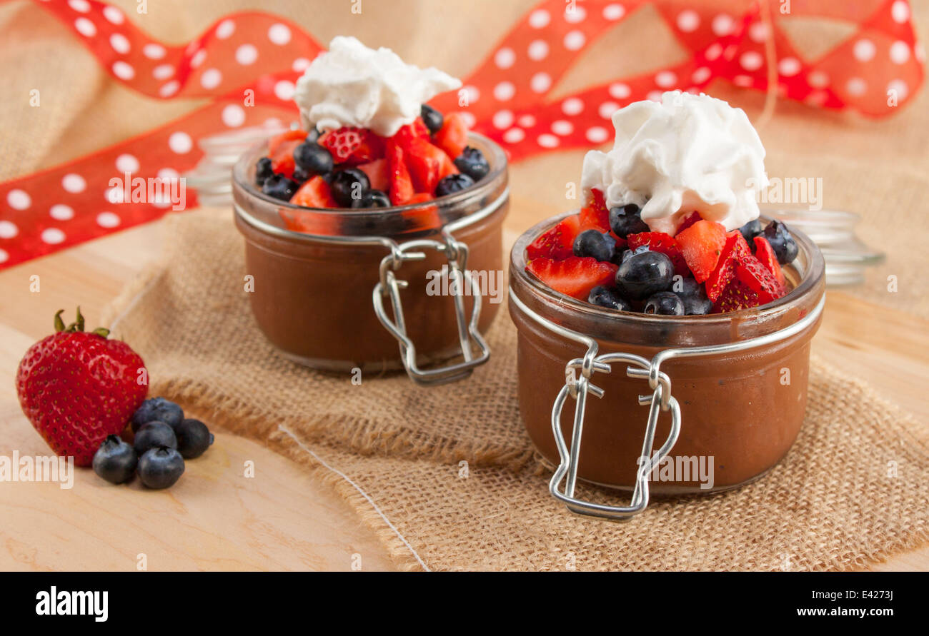 Mousse au Chocolat in niedlichen Container mit Heidelbeeren, Erdbeeren und Schlagsahne gekrönt. Vegan. Stockfoto
