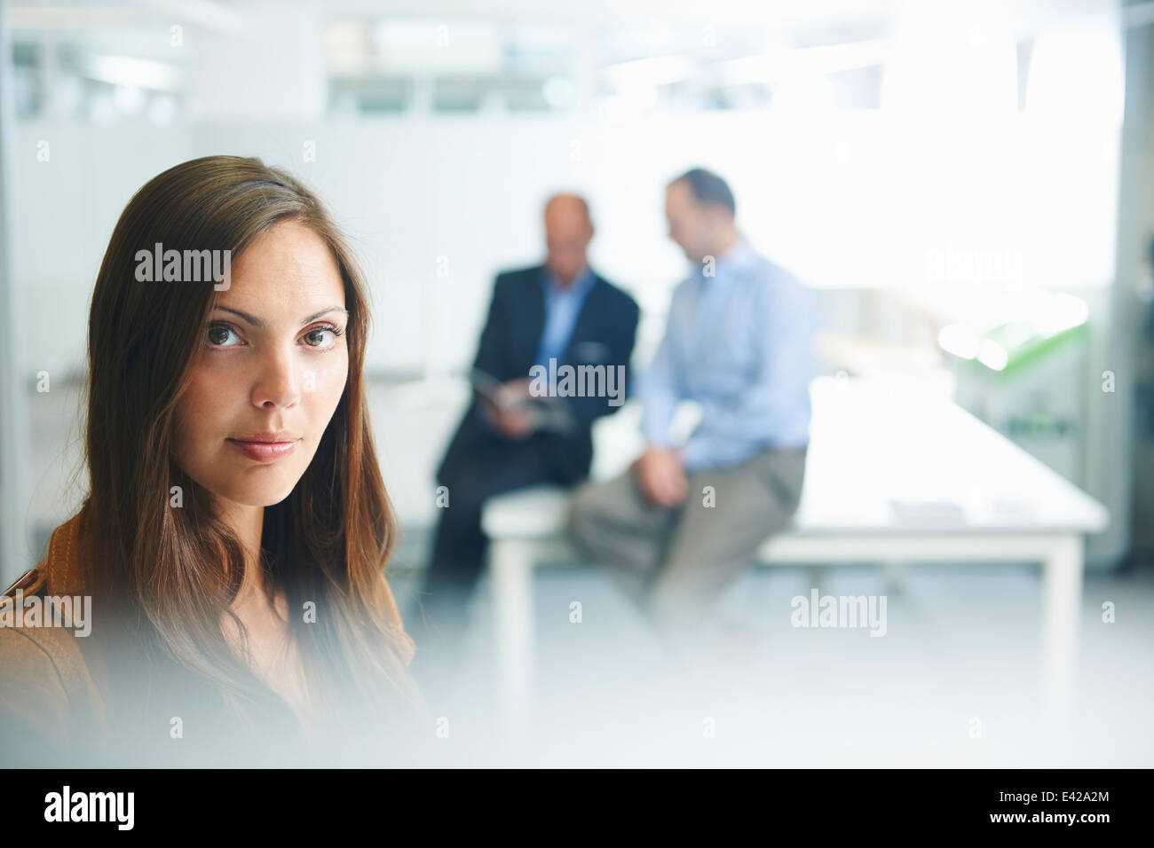 Frau posiert für die Kamera, Geschäftsleute im Hintergrund Stockfoto