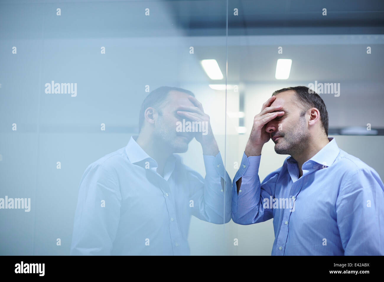 Mann verzweifelt vor reflektierenden Wand Stockfoto