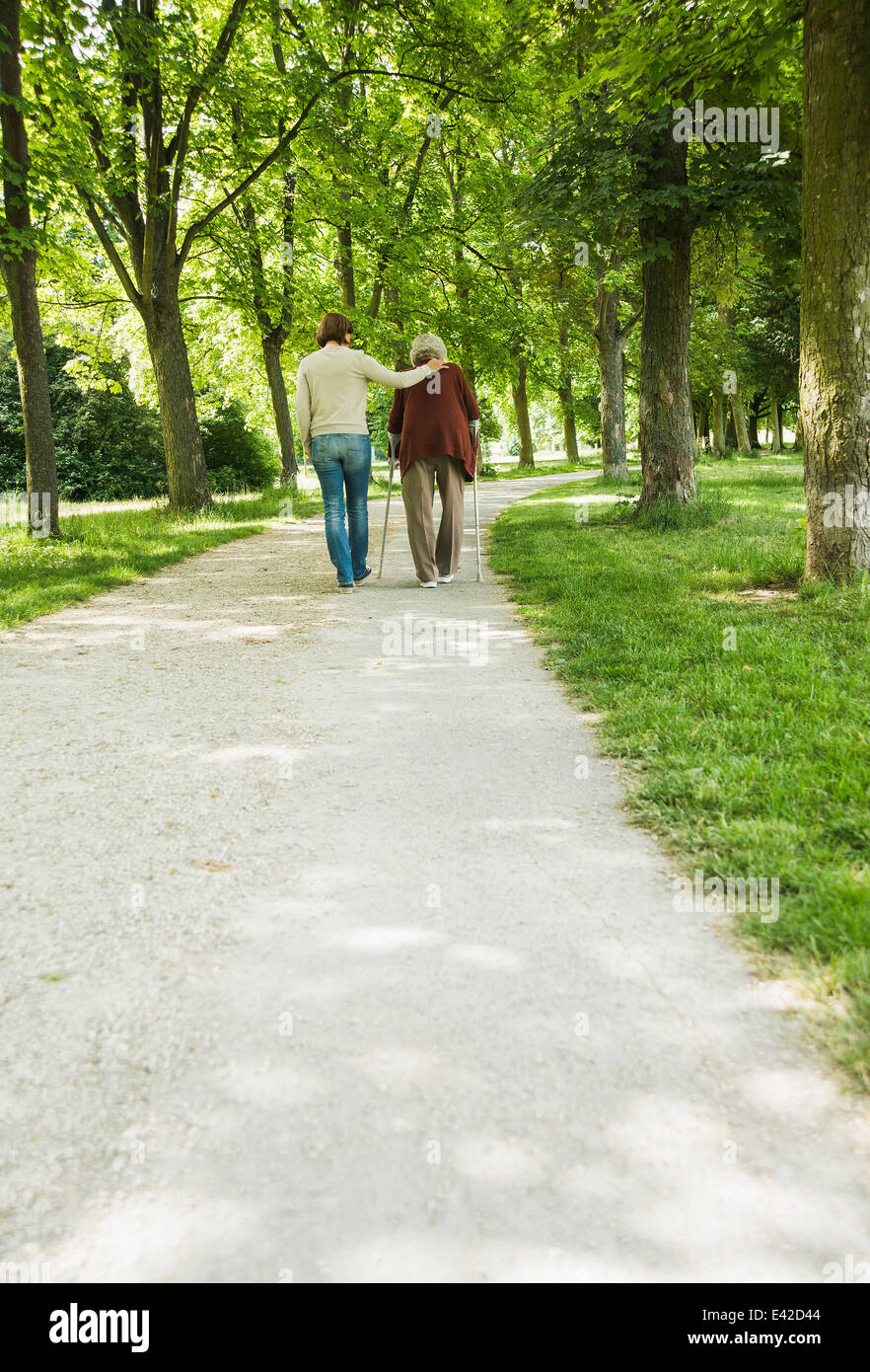Ältere Frau und Enkelin zu Fuß durch den Park, mit Spazierstock Stockfoto