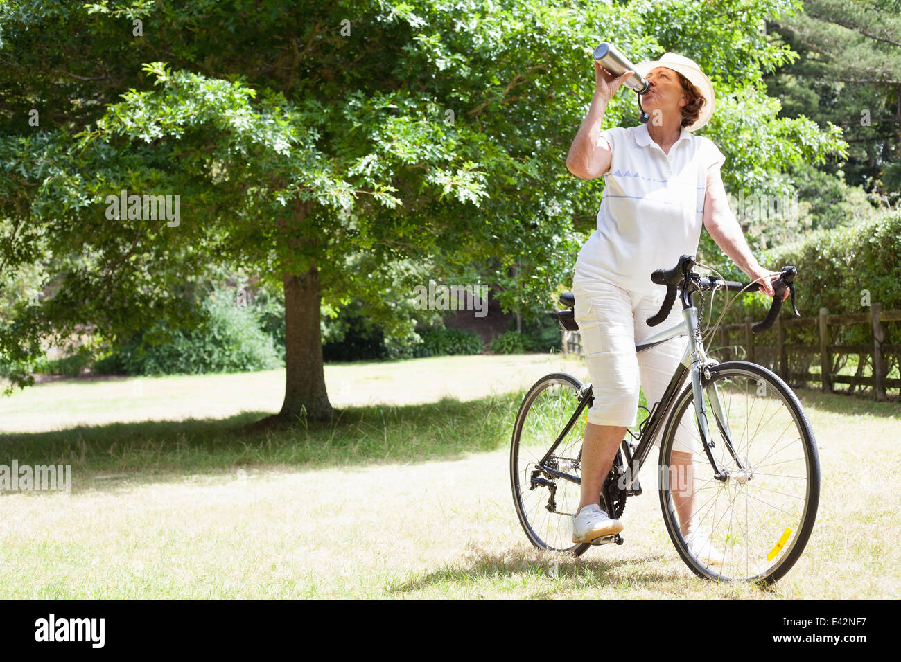 Ältere Frau Radfahrer Trinkwasser im park Stockfoto