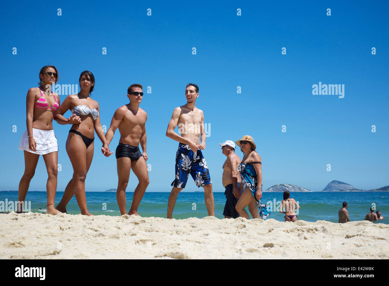 RIO DE JANEIRO, Brasilien - 1. Februar 2014: Gruppe von brasilianischen Freunde zu Fuß entlang der Küste an einem Sommertag am Strand von Ipanema. Stockfoto