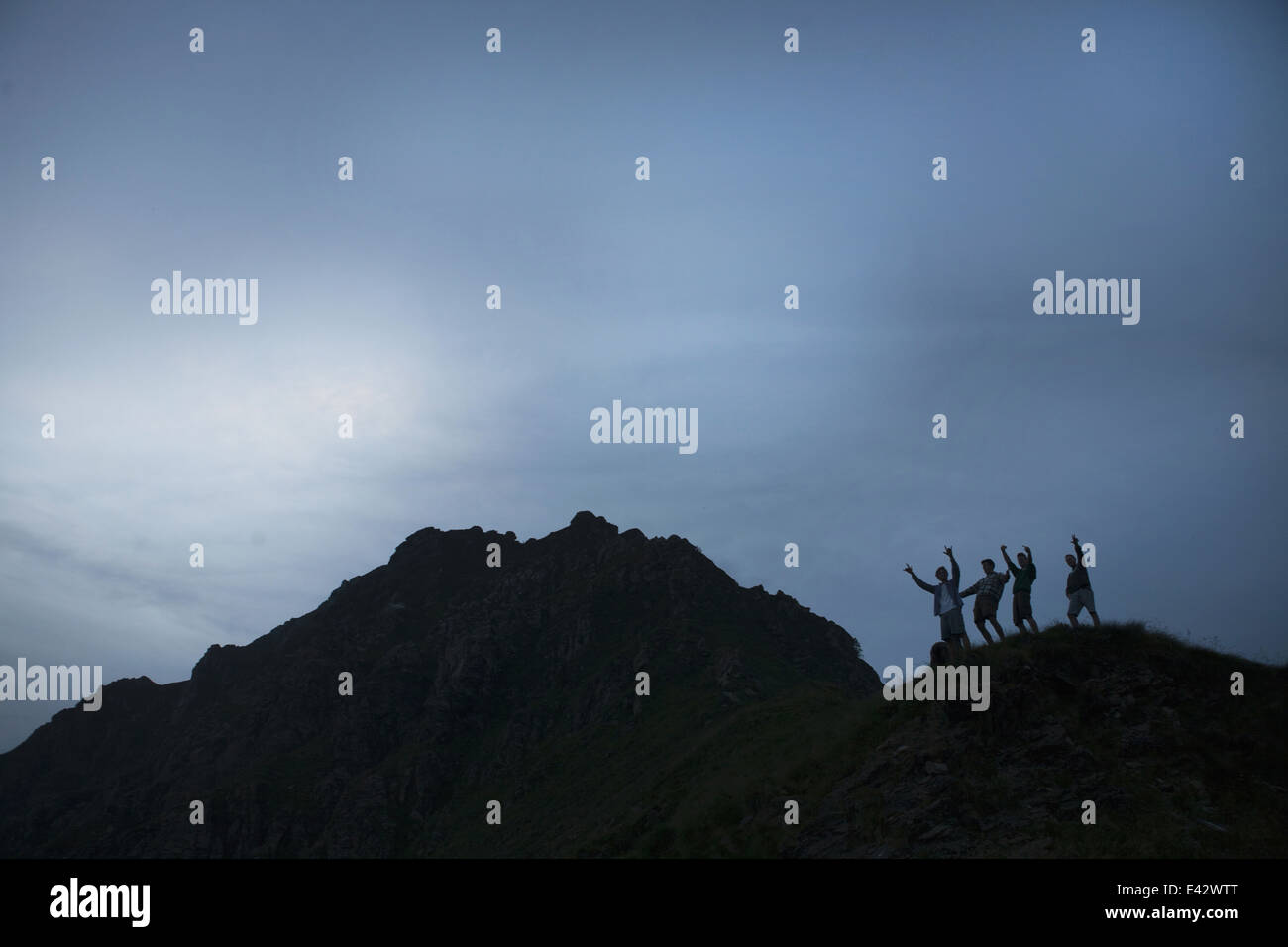 Silhouette von vier jungen Erwachsenen Männern mit Armen angehoben auf Berg Stockfoto
