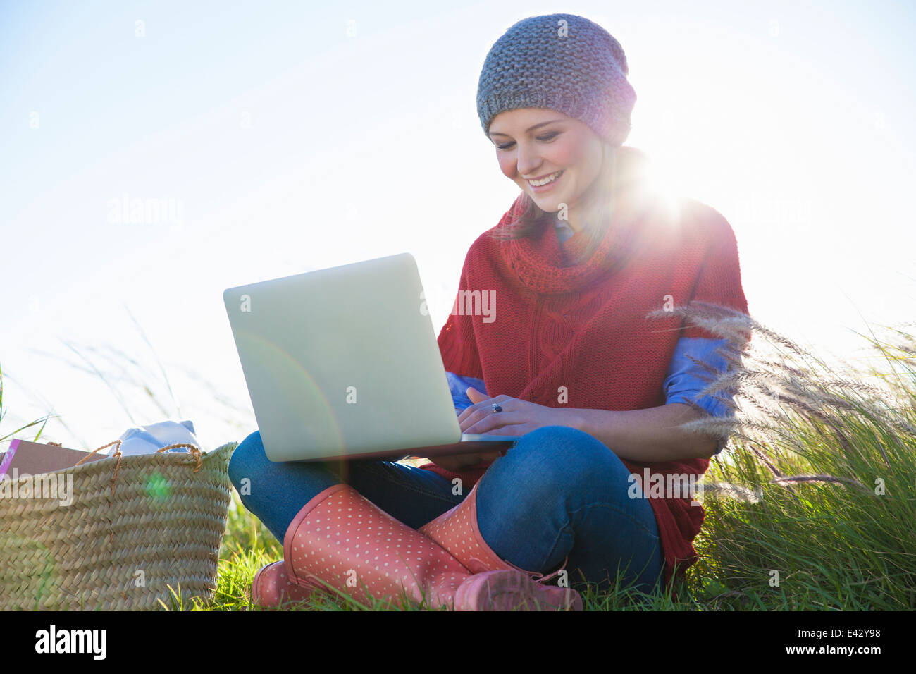 Junge Frau mit Laptop lange Gras sitzend Stockfoto