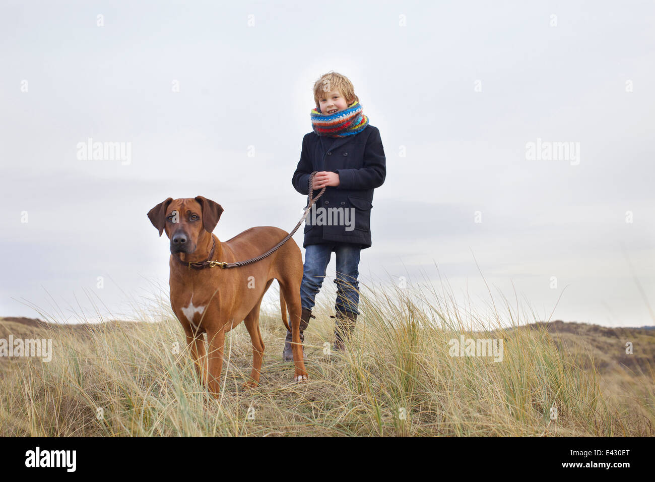 Junge Spaziergang mit seinem Hund in Sanddünen an der Küste Stockfoto