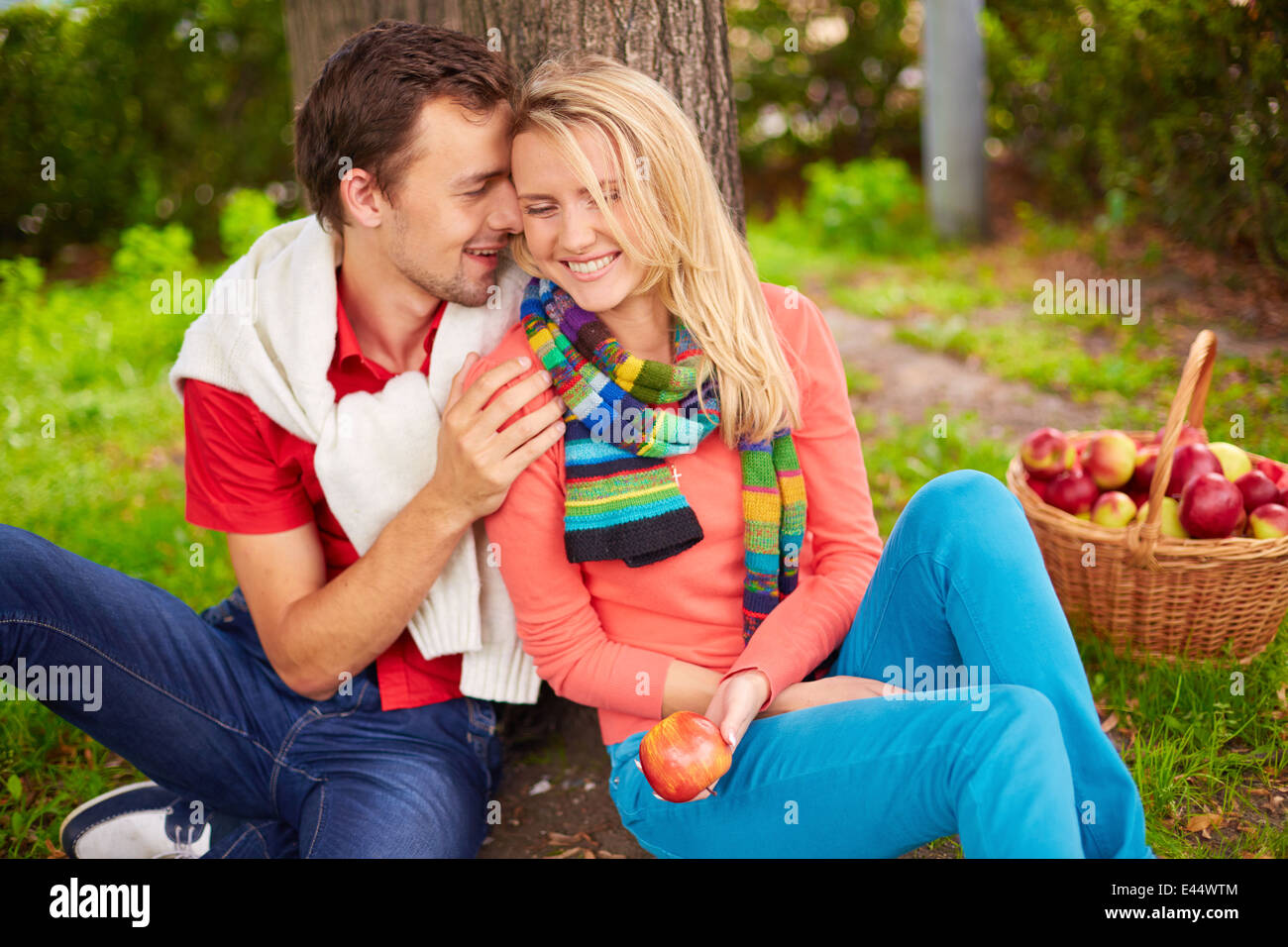 Glückliches junges Paar im Park sitzen und flirten Stockfoto