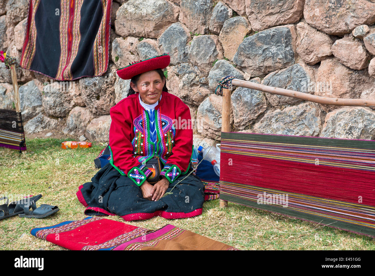 Ältere Frau mit einem Hut, Quechua-Indianer in traditioneller Kleidung, sitzen auf dem Boden vor der Bahre eines Webstuhls Stockfoto