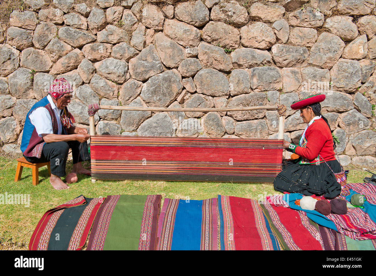 Zwei Quechua-Indianer im traditionellen Kleid hocken auf dem Boden auf der Bahre von Webstuhl, gewebten Decken mit typischen arbeiten Stockfoto
