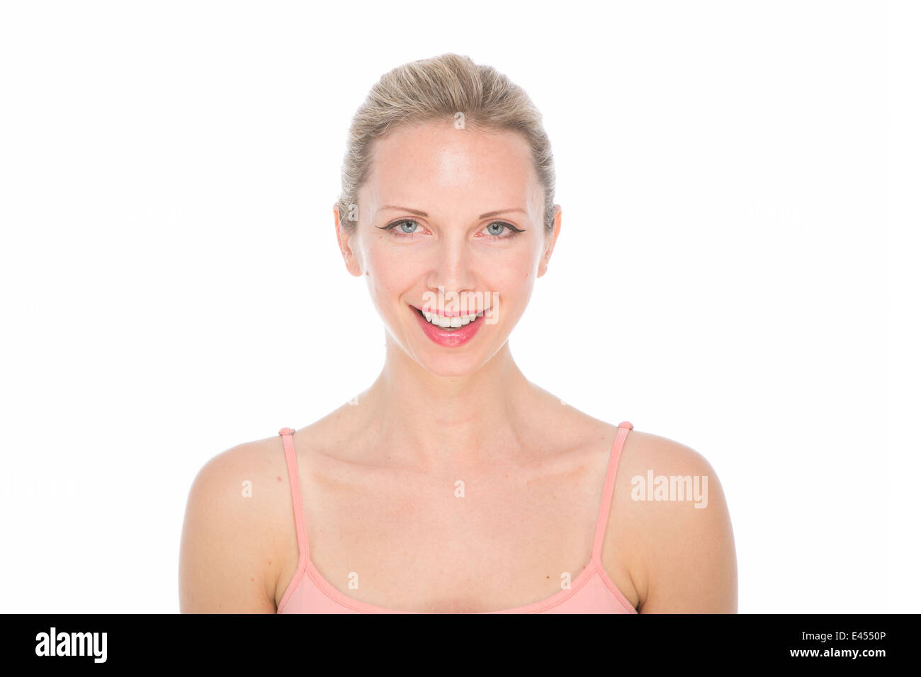 attraktive junge blonde Frau in rosa Weste Top mit Haar gebunden zurück von Gesicht und natürliches Make-up Lächeln mit weißen Zähnen Stockfoto