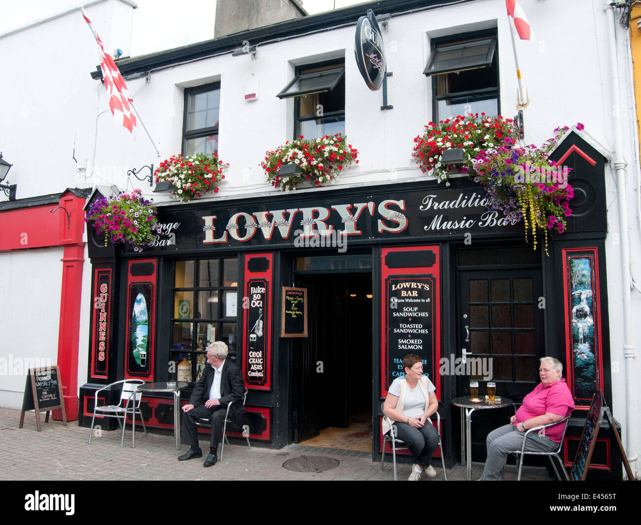 Menschen trinken ein Bier vor einem Irish Pub in Clifden, Irland Stockfoto