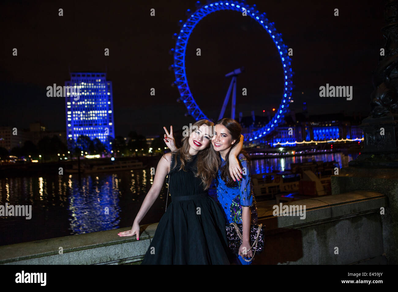 Porträt von zwei Freundinnen posieren mit London Eye in der Nacht, London, UK Stockfoto