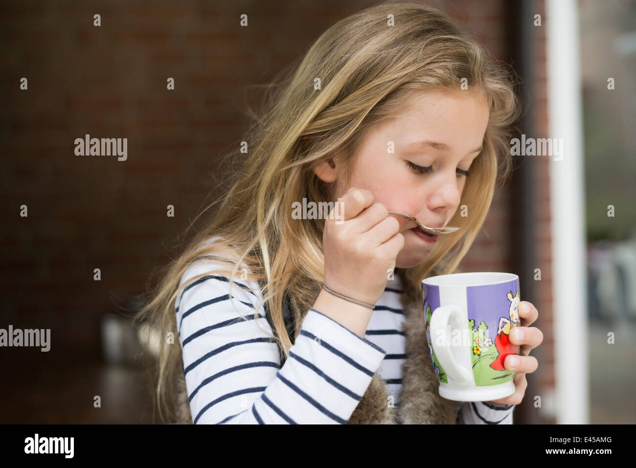 Mädchen Löffel trinken aus Becher Stockfoto