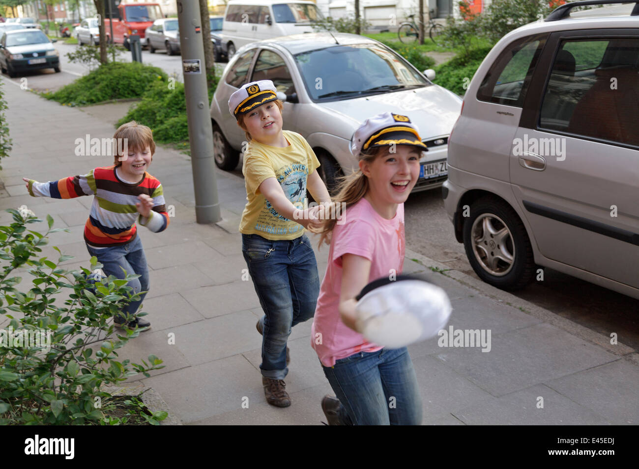 drei glückliche Kinder, die entlang einer Straße Stockfoto
