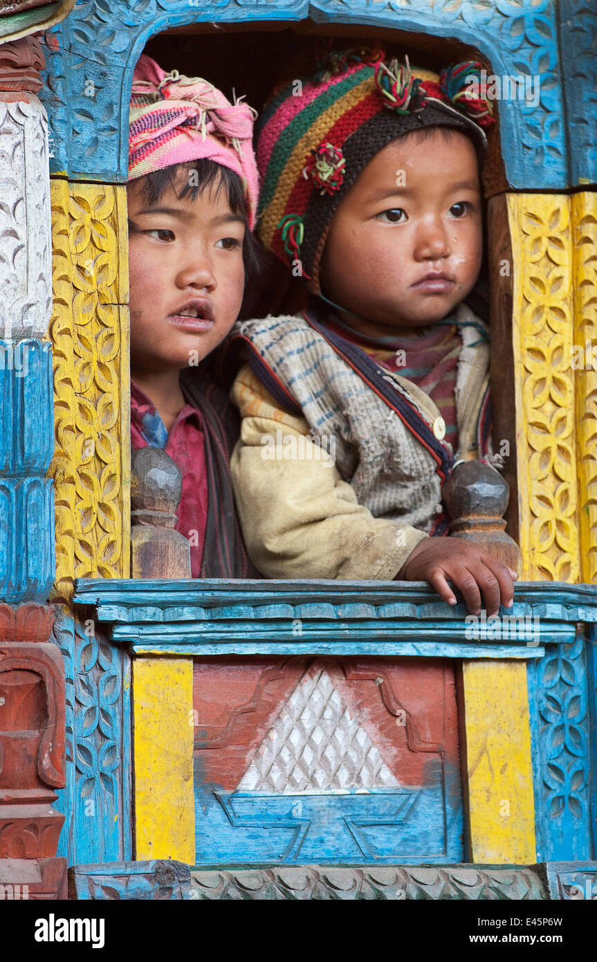 Zwei Kinder durch geschmückten Fenster der traditionellen Gebäude. Tamang ethnische Gruppe, Gadlang, Langtang Gebiet, Nepal. November 2009 Stockfoto