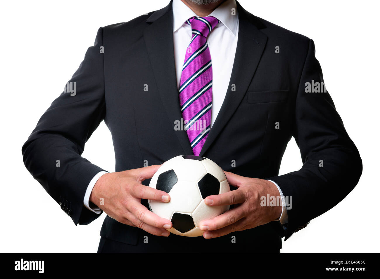 Business-Mann im dunklen Anzug und Krawatte hält einen Fußball Stockfoto