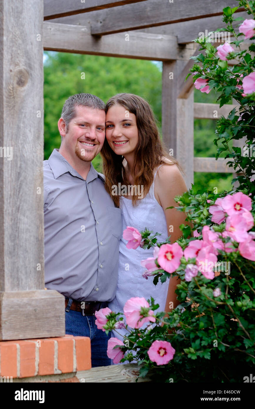 Eine Konzepte Bild einer glücklichen, liebevollen Paar in ihrem 20s für Engagement Bilder in einem wunderschönen Park, umgeben von bunten Blumen darstellen. USA. Stockfoto