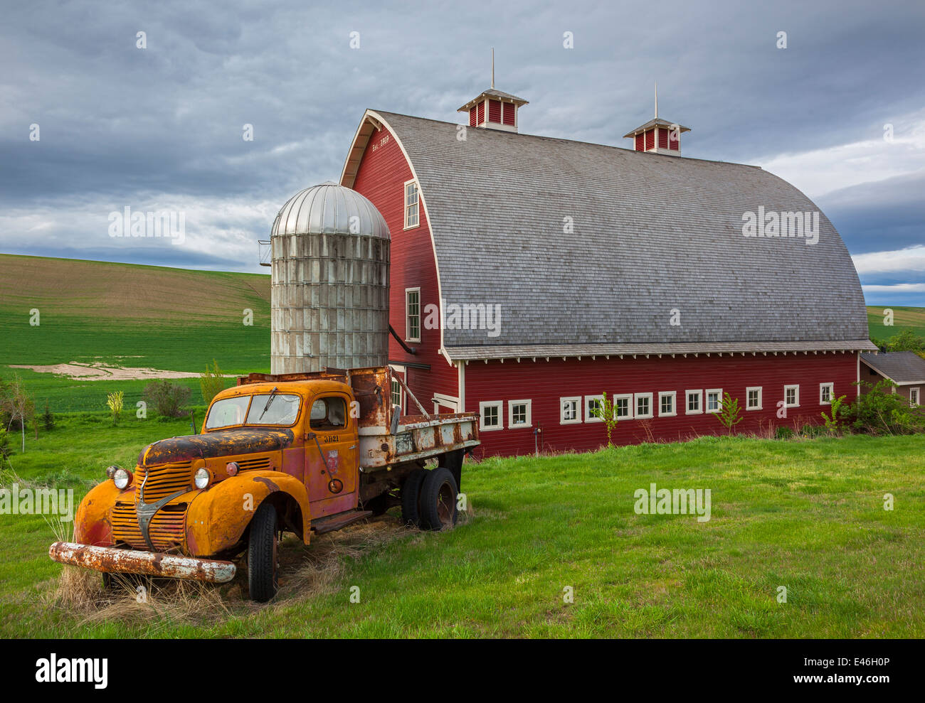 Palouse, Whitman County, WA: Vintage-Tieflader vor roten Scheune und Silo im Sommer, Palouse Land Stockfoto