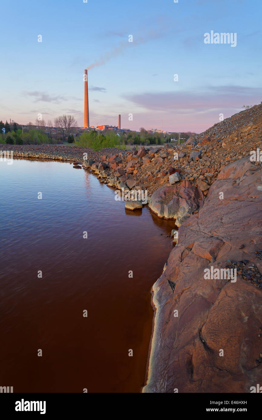 Schweren Rost farbige Sediment am unteren Rand einer Halde Teich drehen eine unnatürliche braune Farbe mit der Superstack sichtbar. Stockfoto