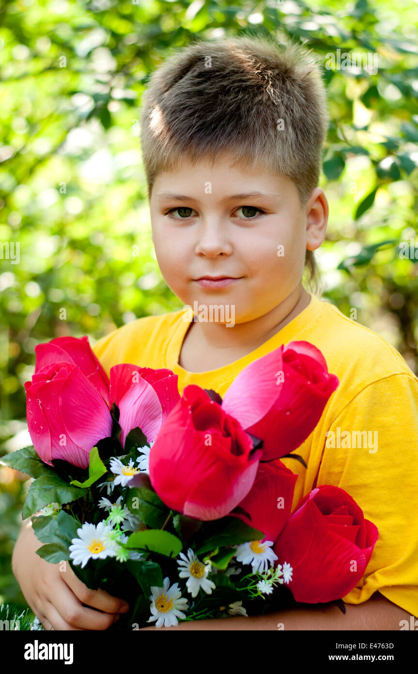 junge Kind einer achtjährigen blonder Mann Waldpark Bäume Laub Sommer Tag sonniges Gemüt Blumen Rosensträuße künstliche Porträt Stockfoto