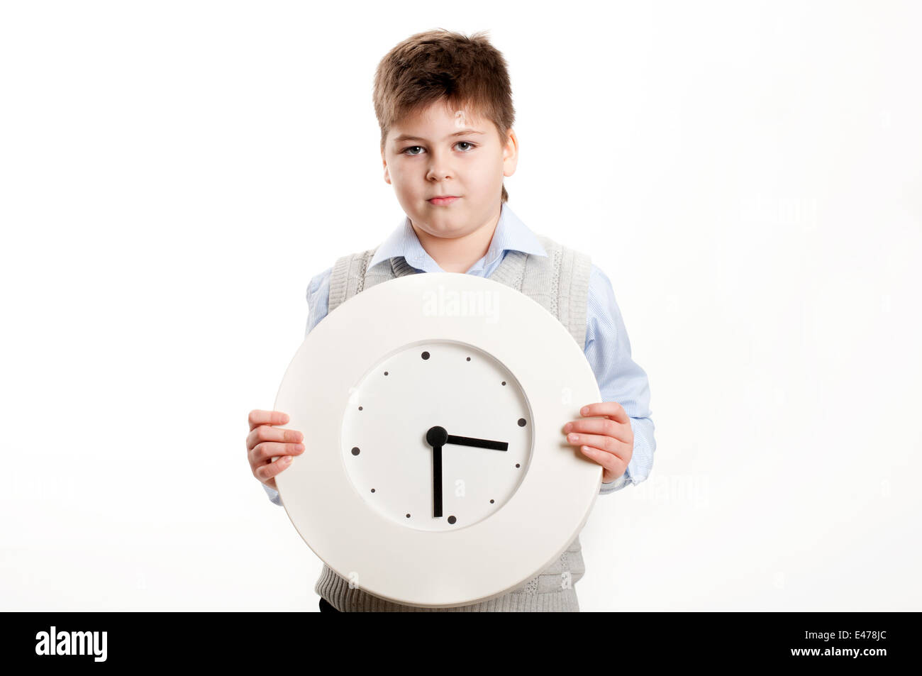 junge Kind Uhr Schüler Hintergrundbeleuchtung Hände einmal weißen Hemd Weste Form blond Schule zeigt halten rund 8 Jahre halten Sie Lächeln Stockfoto