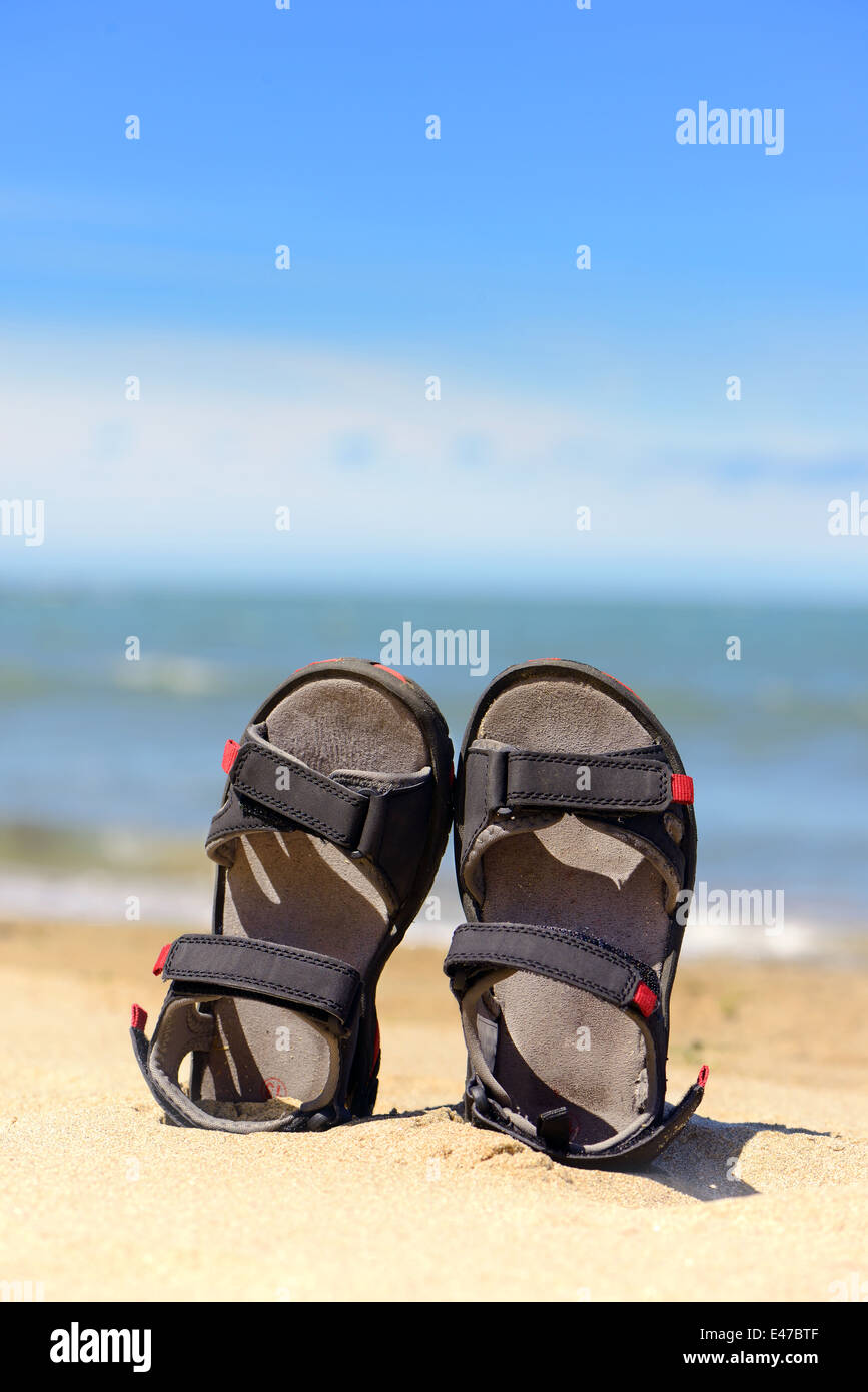 Sandalen, die während des Spielens auf den Urlaub am Meer im Sand hinterlassen Stockfoto