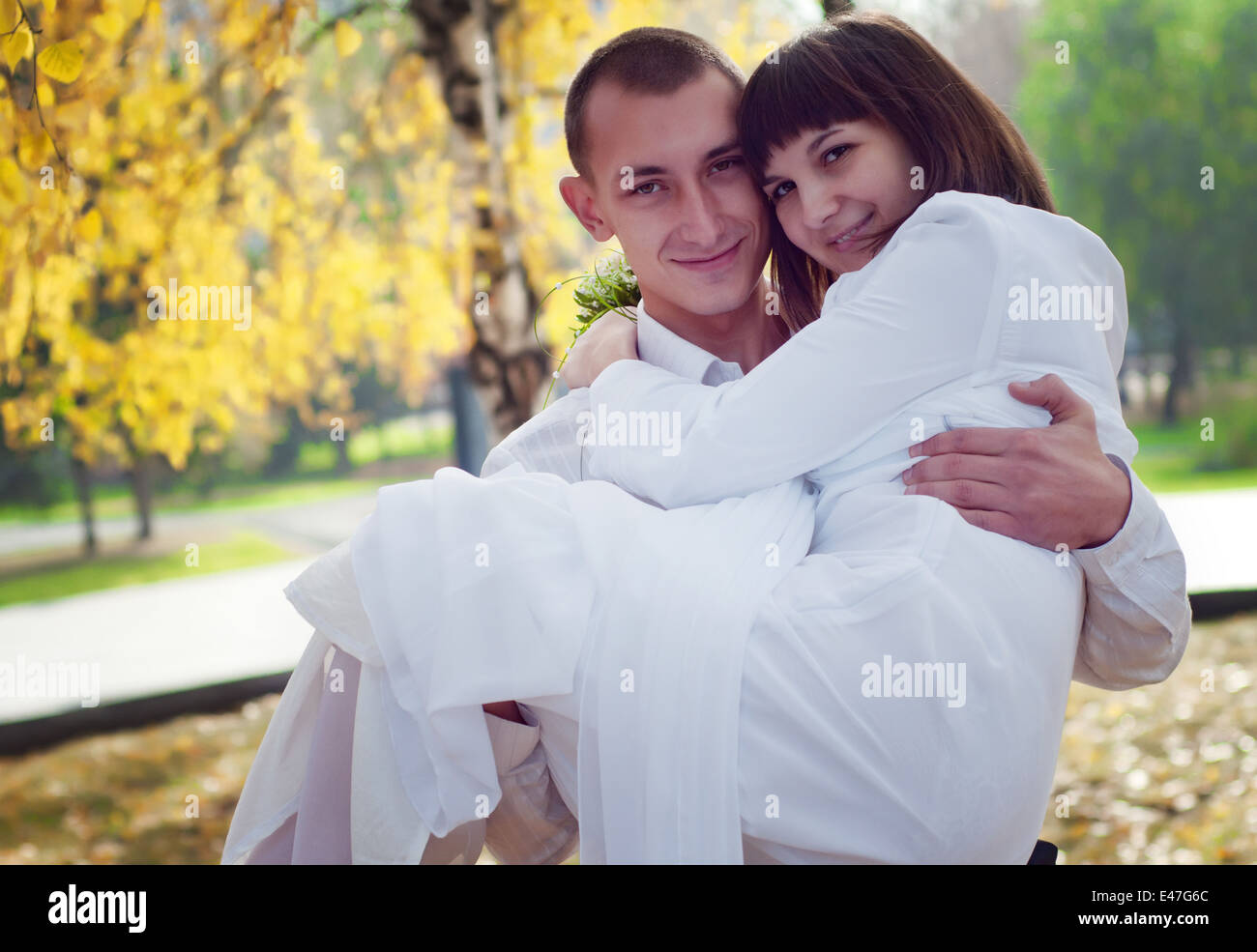 Schöne europäische junge Brautpaar, Bräutigam trägt seine Braut, Herbst Stockfoto