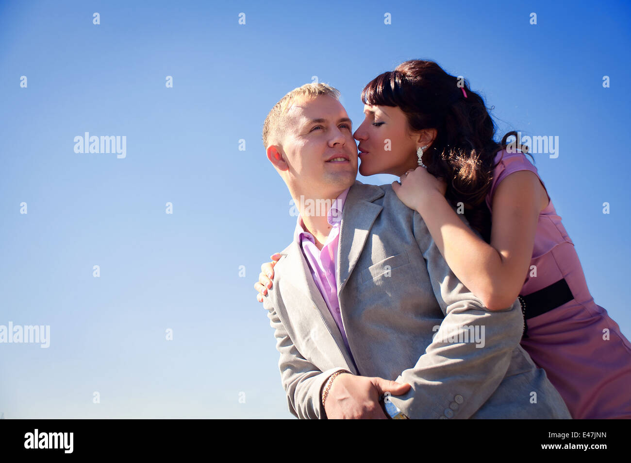 Frau ist ihr Freund küssen auf den blauen Himmelshintergrund Stockfoto