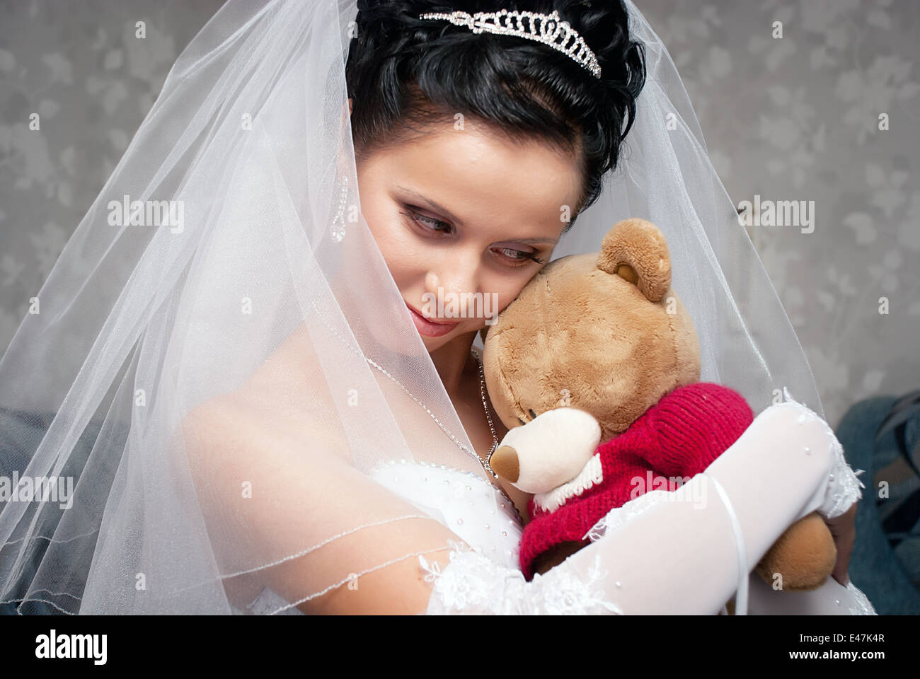 Porträt der schönen europäischen Braut umarmt Spielzeug Bär Stockfoto