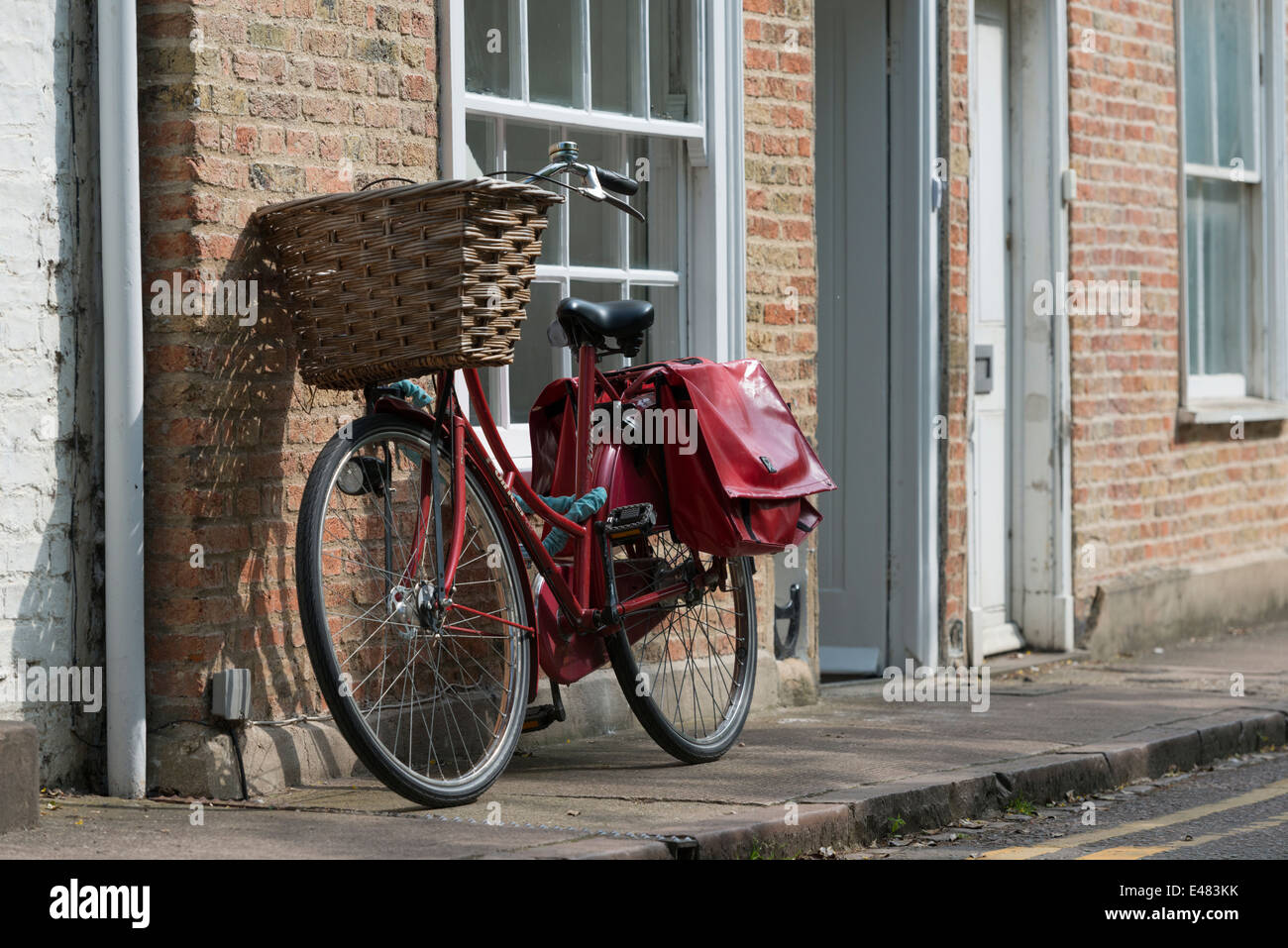 Ein Fahrrad, eine Wand in Cambridge UK mit roten Packtaschen gelehnt Stockfoto