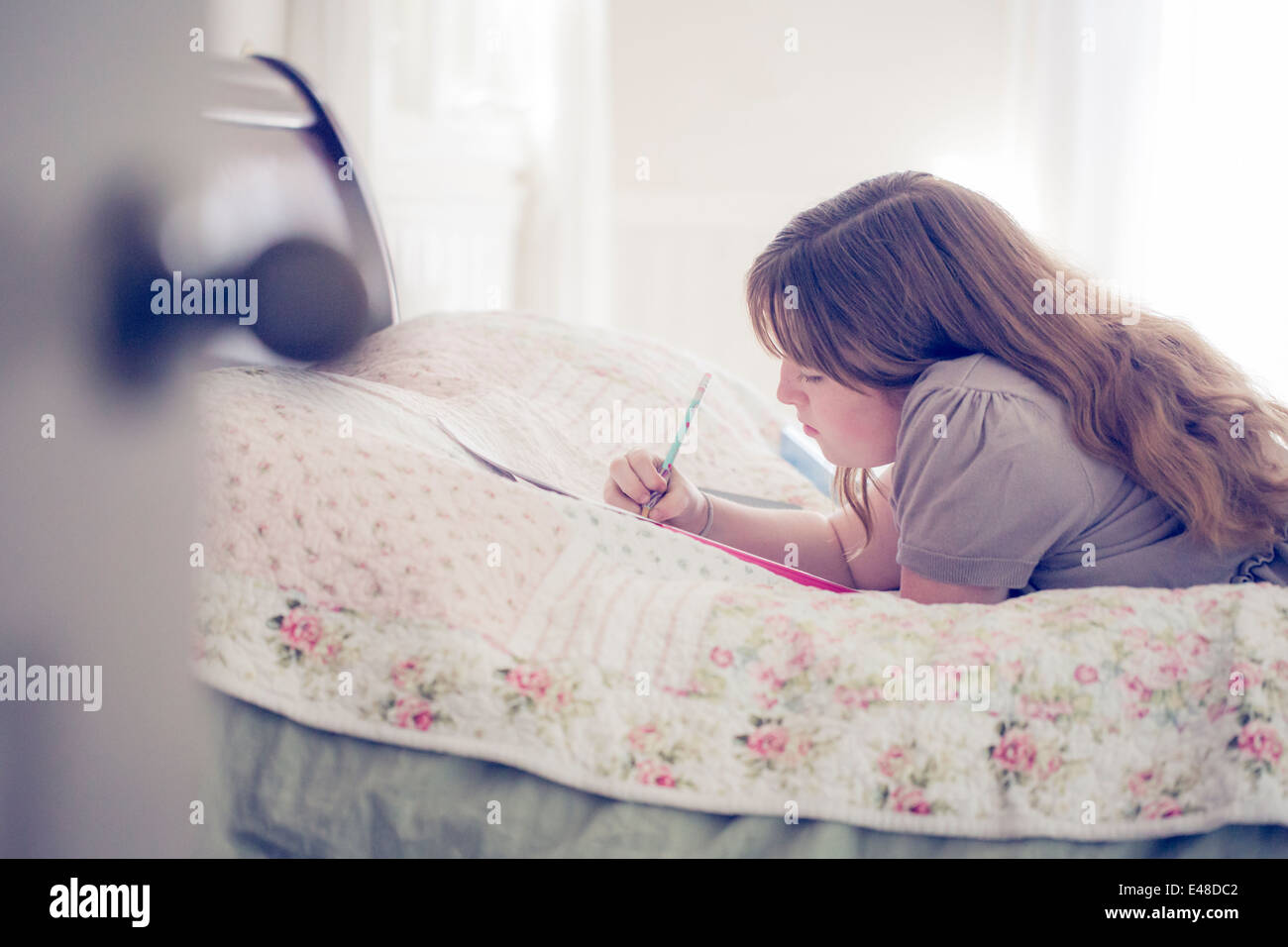 Teenager-Mädchen (13-15) im Bett liegen und schreiben Stockfoto