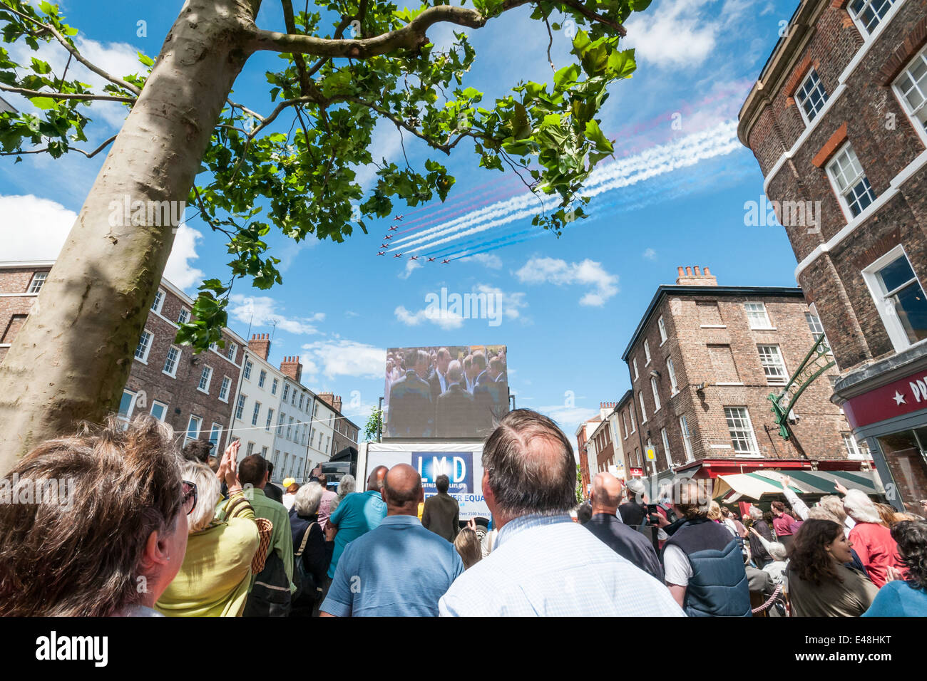 Menschen zu sehen, der Tour de France am Bildschirm in York mit Red Arrows fliegt über die Stadt Stockfoto