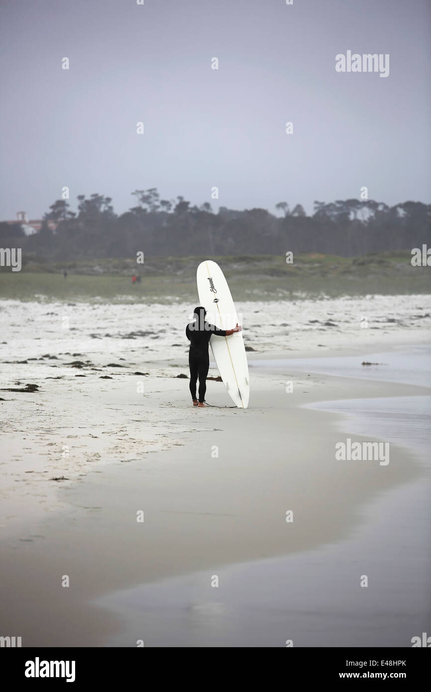 Surfer im Neoprenanzug steht auf der Sandstrand Küste mit Surfbrett in Pacific Grove von Pebble Beach in Kalifornien Stockfoto