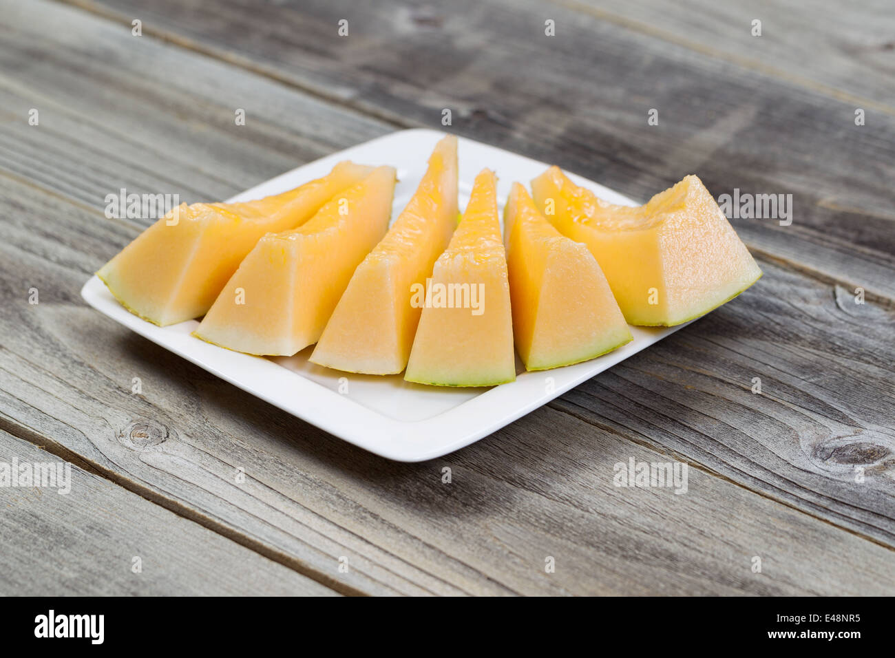 Detailansicht einer frisch geschnittenen Melonenscheiben auf weißen Teller auf rustikalen Holz Stockfoto