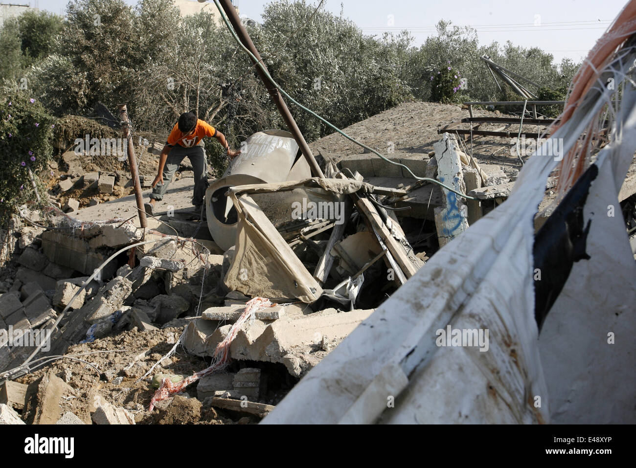 7. Juli 2014 - Gaza, Gazastreifen, Palästinensische Autonomiegebiete - ein palästinensischer junge Mann inspiziert den Trümmern eines zerstörten Gebäudes nach einem israelischen Luftangriff in Rafah, südlichen Gazastreifen am 6. Juli 2014, israelische Kampfflugzeuge griffen drei Standorte im südlichen Gazastreifen, targeting Trainingslager der Ezzedine al-Qassam Brigaden, der militärische Flügel der Hamas, in Rafah und Khan Yunis, sowie ein leeres Feld in Khan Yunis. Seit eine Welle in militanten Raketenbeschuss aus dem Gazastreifen und Vergeltungsmaßnahmen israelische Luftangriffe die Entführung und Ermordung von drei israelischen Jugendlichen eine große Razzia auf Hamas aufgefordert Stockfoto