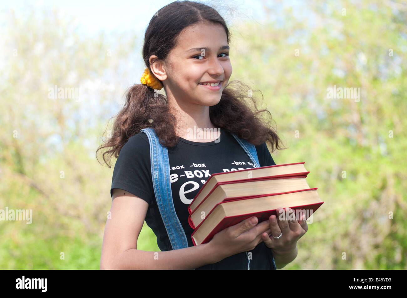 ein Mädchen Bücher Schule Schulmädchen Open-Air Teenager lernen Lesung Lehrbücher studieren hält Stapeln Brünette dunkelhäutige 12 ye Stockfoto