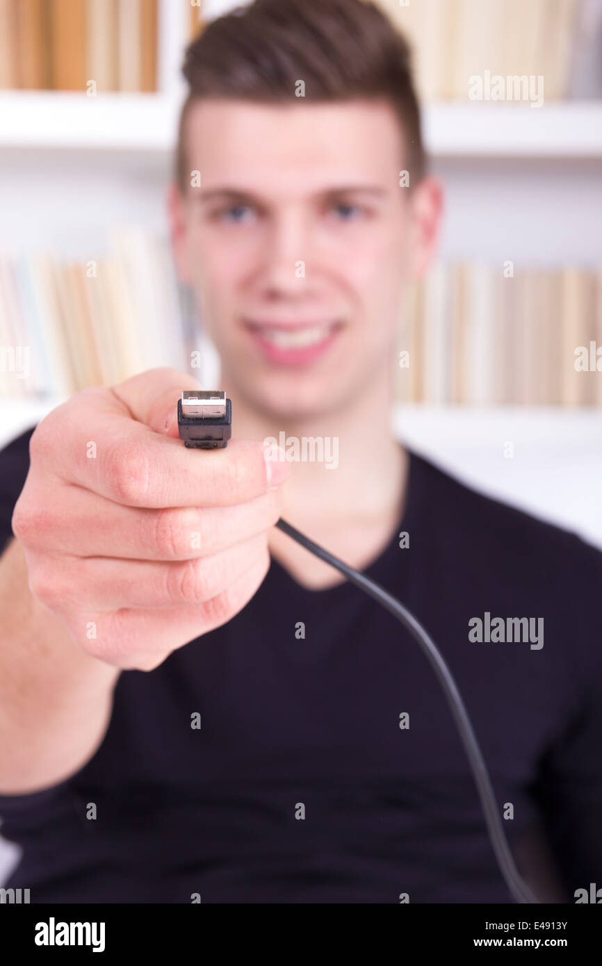 Mann hält und zeigt schwarzen USB-Kabel, USB-Anschluss Stockfoto