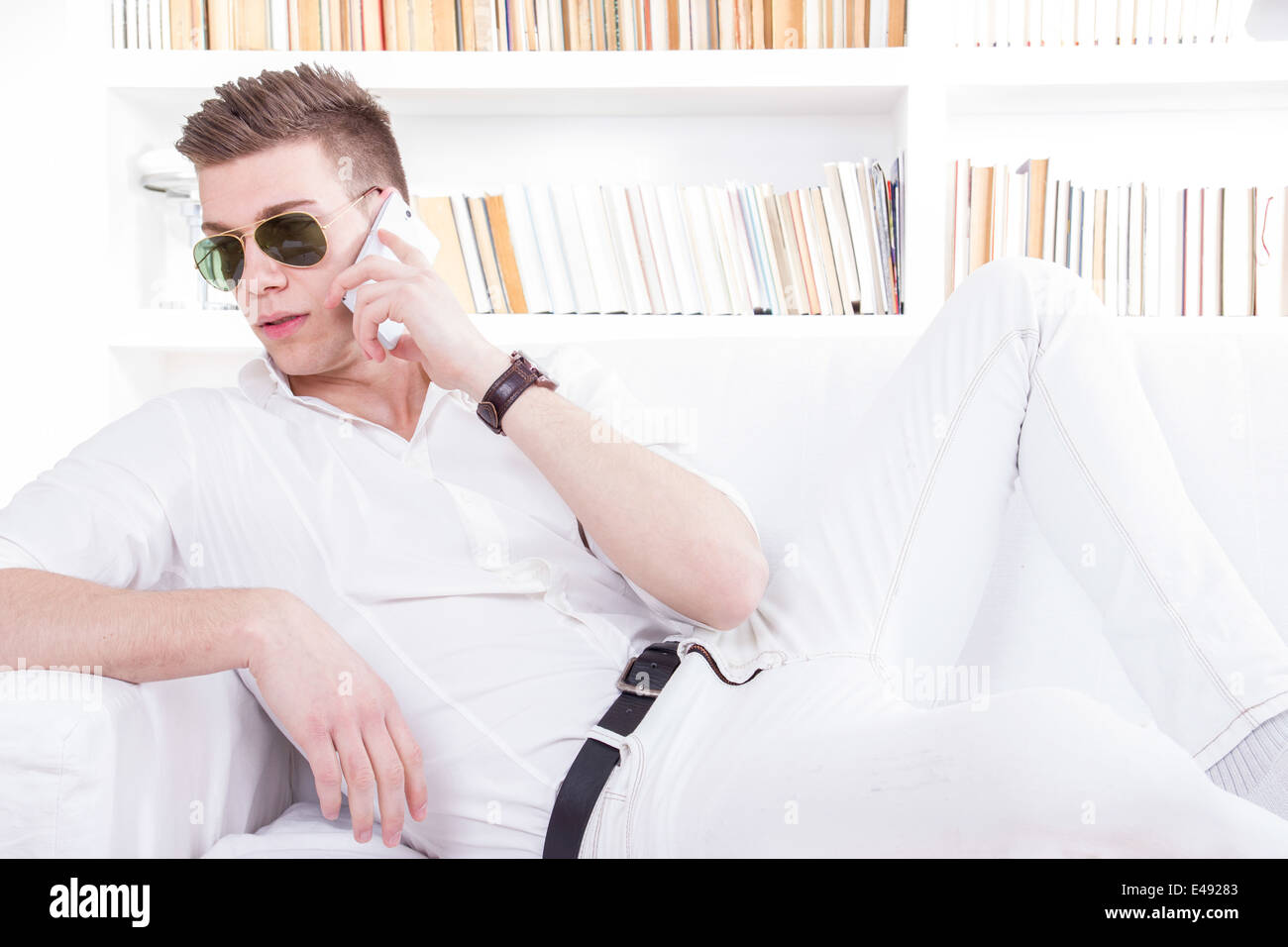 Mode-Mann mit Sonnenbrille am Telefon sprechen entspannt zu Hause Stockfoto