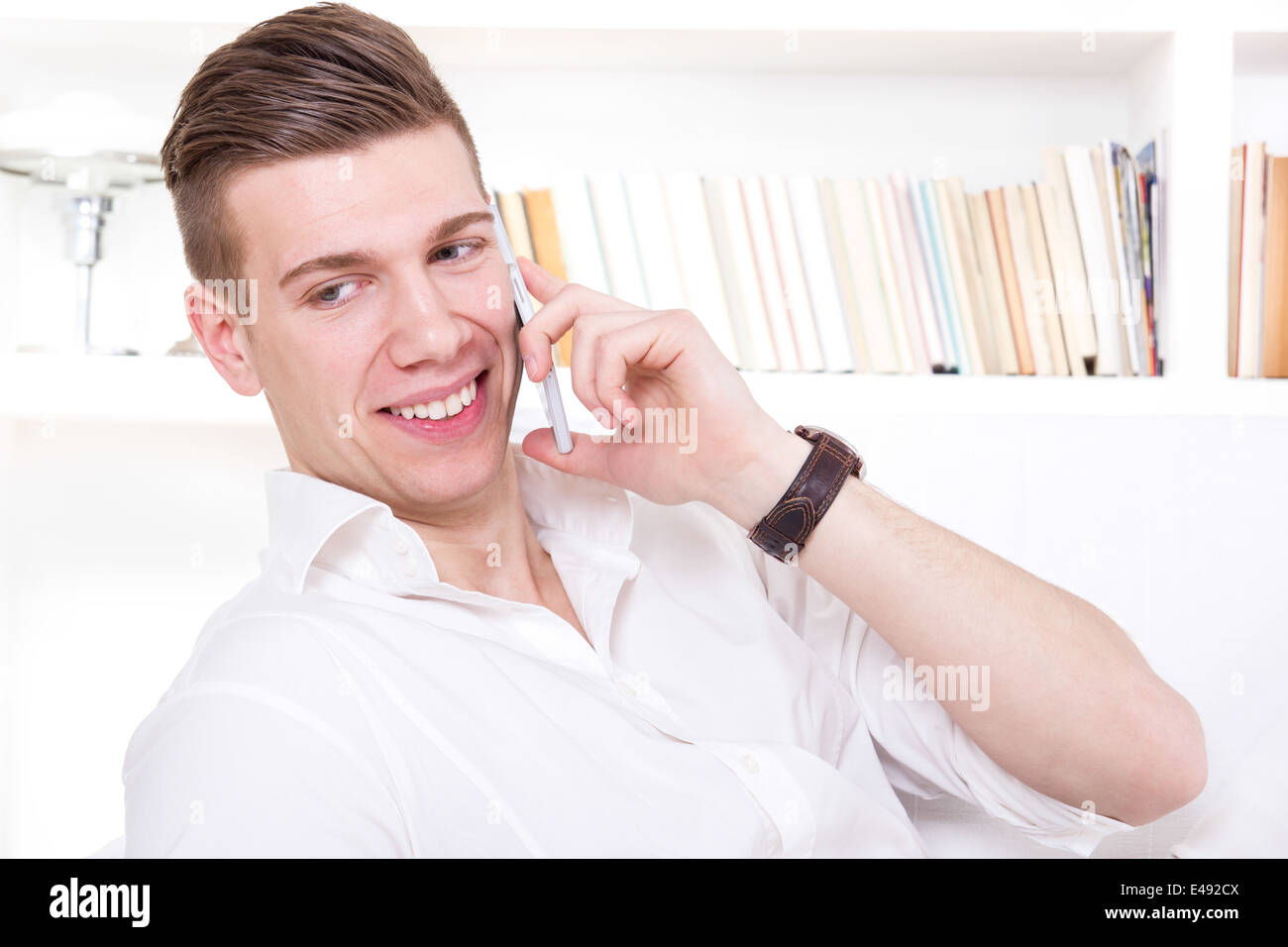 glücklich, gut aussehender Mann im weißen T-shirt Lächeln am Telefon sprechen Stockfoto