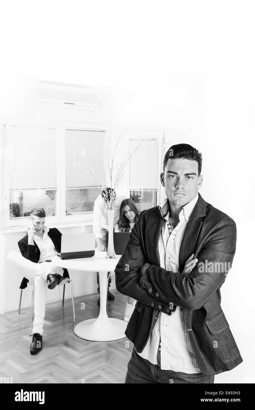 ernsthafte erfolgreicher Geschäftsmann getrennt vom Team Menschen hinter ihm Arbeitsstil, schwarz / weiß Stockfoto