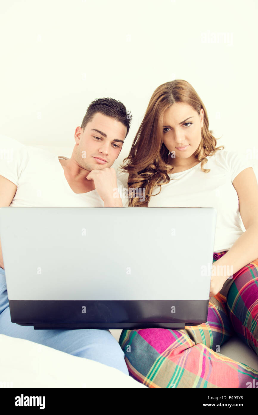 Lässige junge Paar mit Laptop-Computer im Bett für das Internet und Filme zu genießen Stockfoto