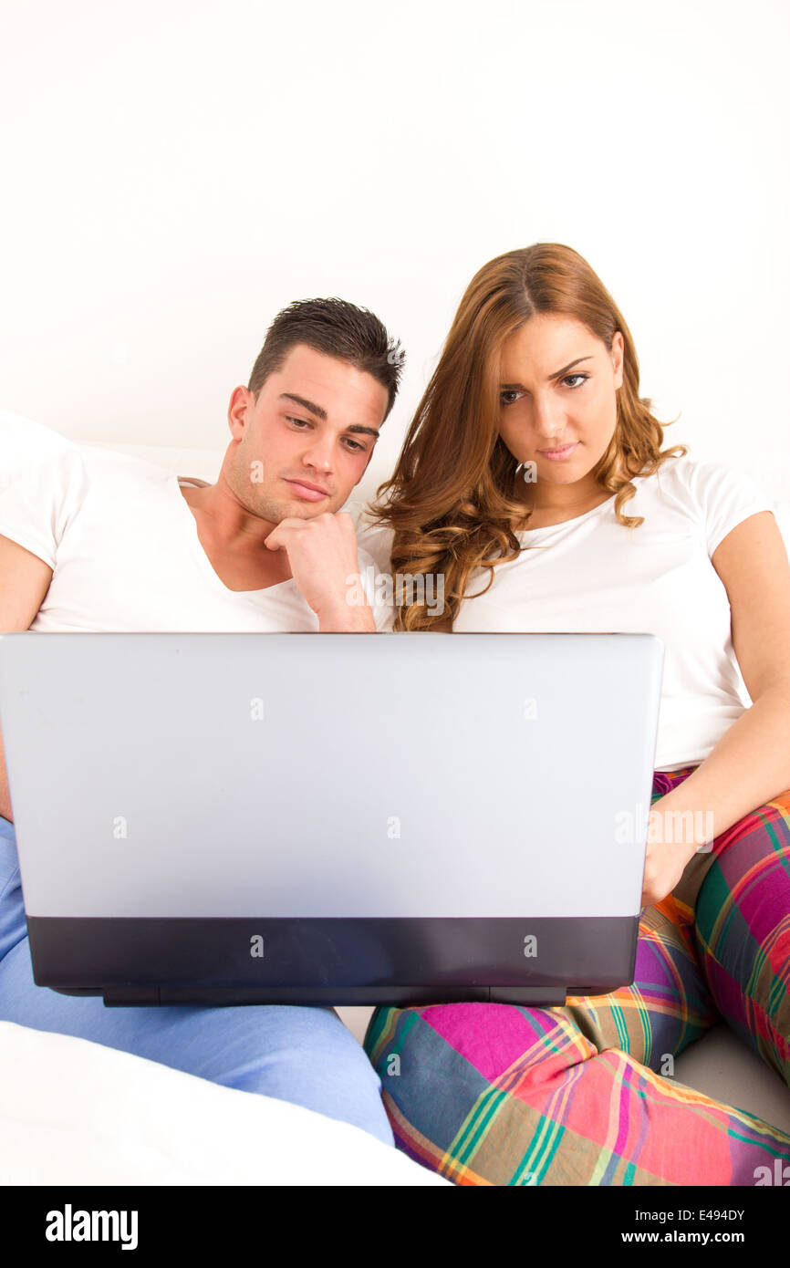 Lässige junge glückliche Paar mit Laptop-Computer im Bett für das Internet und Filme zu genießen Stockfoto