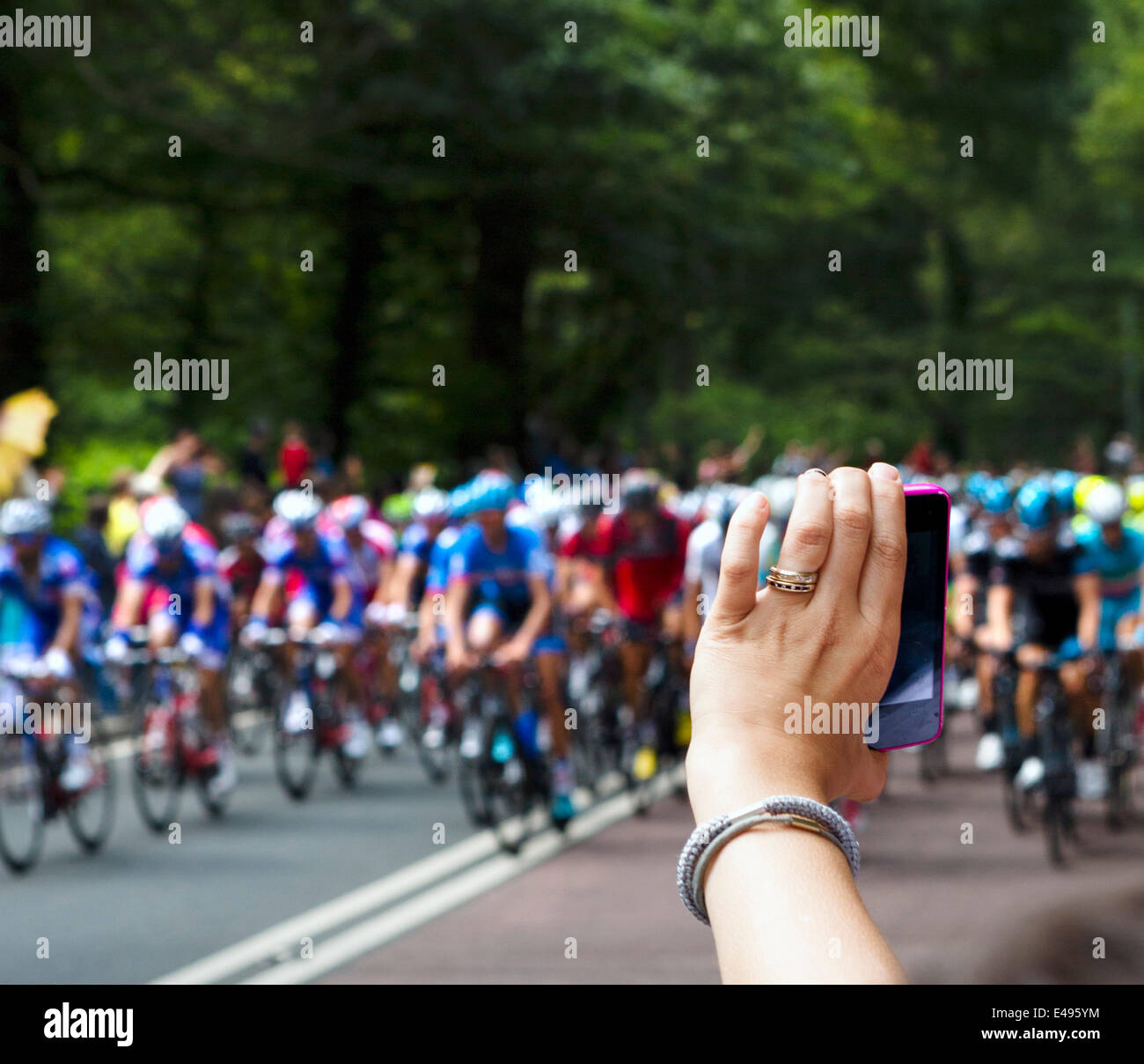 Frau, die ein Foto mit einem Smartphone das Hauptfeld nähert sich Holmfirth am 2. Etappe der Tour de France 2014. Tausende von Menschen die Straßen gesäumt von vielen drängeln, um Fotos der schnellere Fahrer zu machen. West Yorkshire, Großbritannien Stockfoto