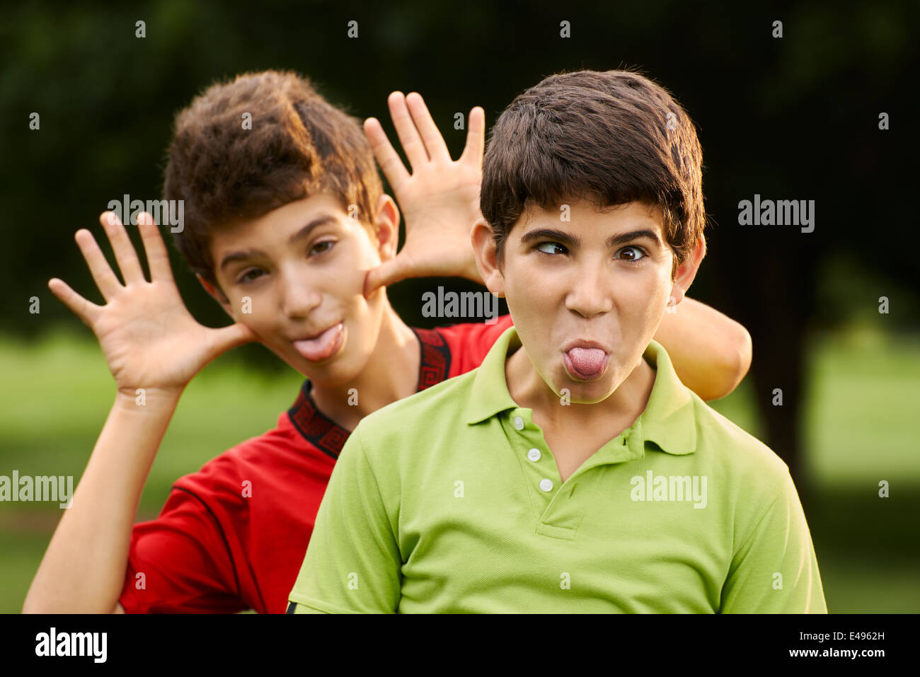 Porträt von glücklichen hispanic Kindern, zwei Brüder, so dass ein Gesicht und verzog das Gesicht in die Kamera draußen im park Stockfoto