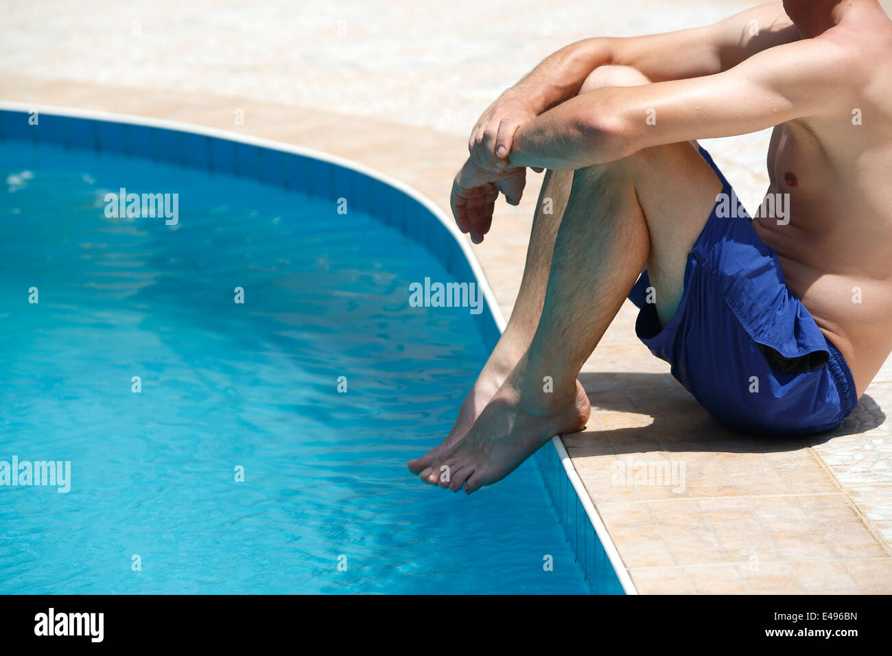 Attraktiver Mann mit blauen Badeanzug genießt Sonne in einem Schwimmbad Stockfoto