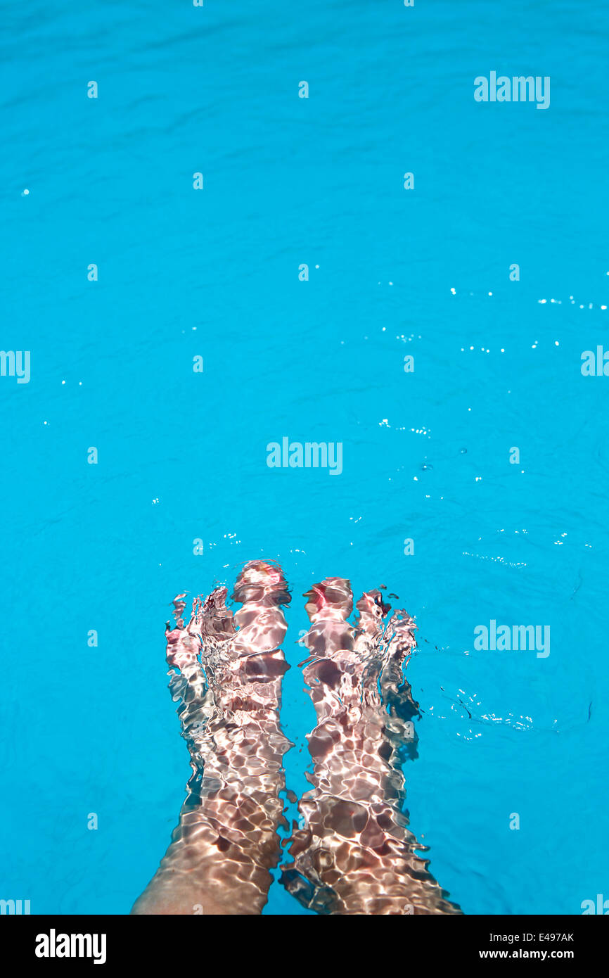 Weibliche Füße im Pool plantschen Stockfoto