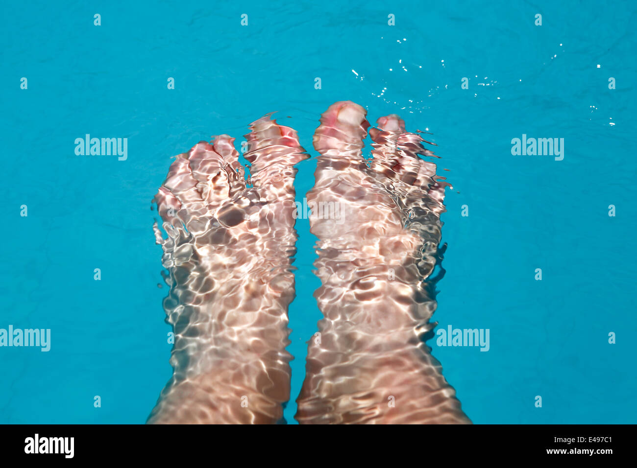 Weibliche Füße im Pool plantschen Stockfoto