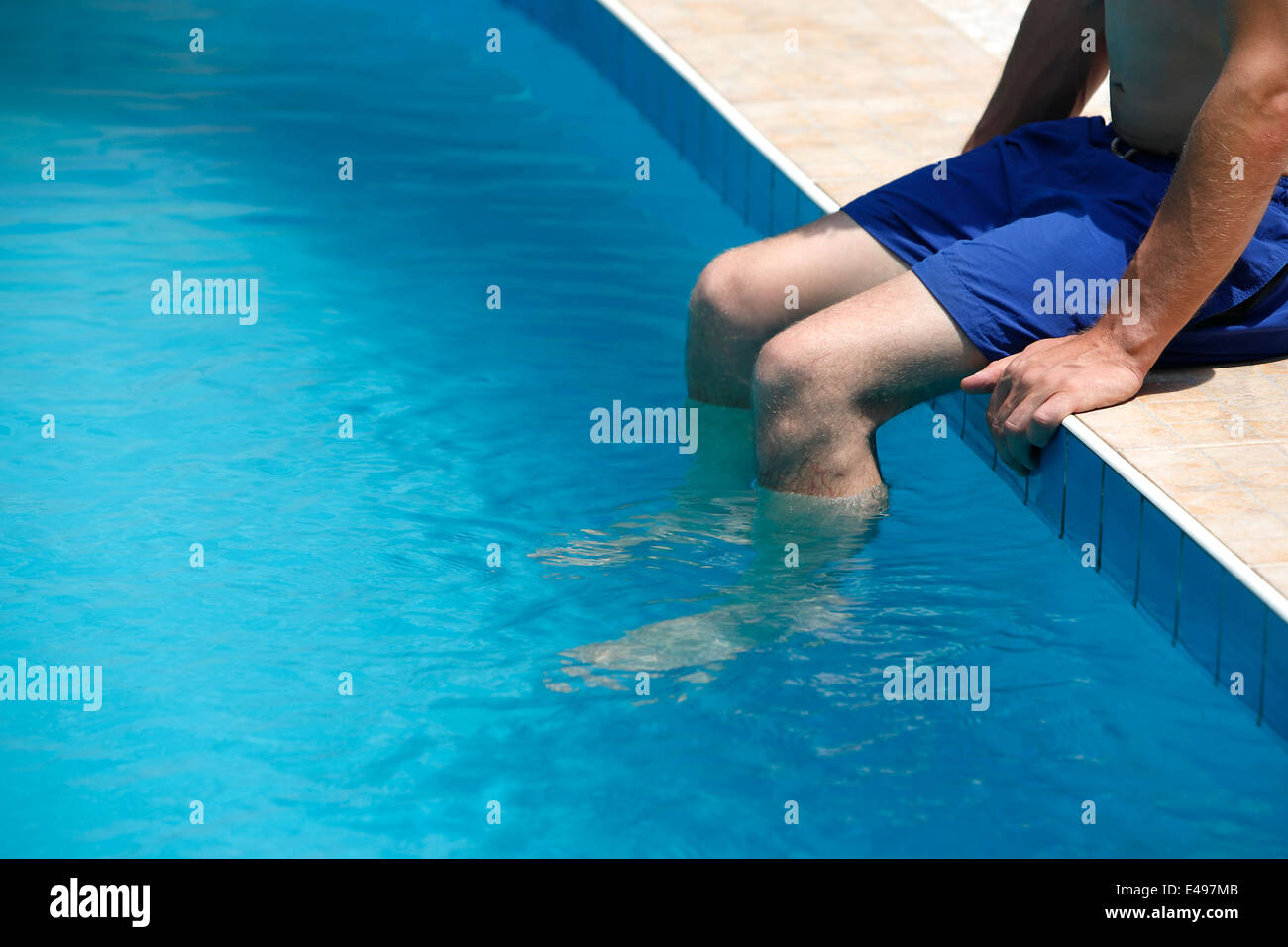 Attraktiver Mann mit blauen Badeanzug genießt Sonne in einem Schwimmbad Stockfoto