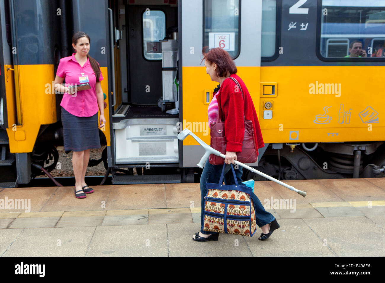 Ältere Frau Fahrgast mit krücke und Dirigent am Bahnhof Plattform Prag, Tschechische Republik Stockfoto