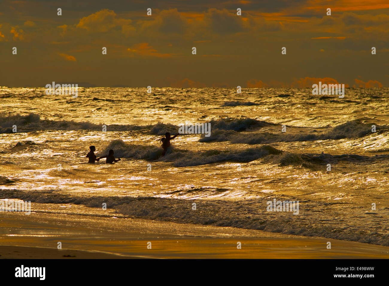 Gruppe von Personen, die während des Sonnenuntergangs am Baltischen Meer baden. Katy Rybackie, Pommern, Polen. Stockfoto