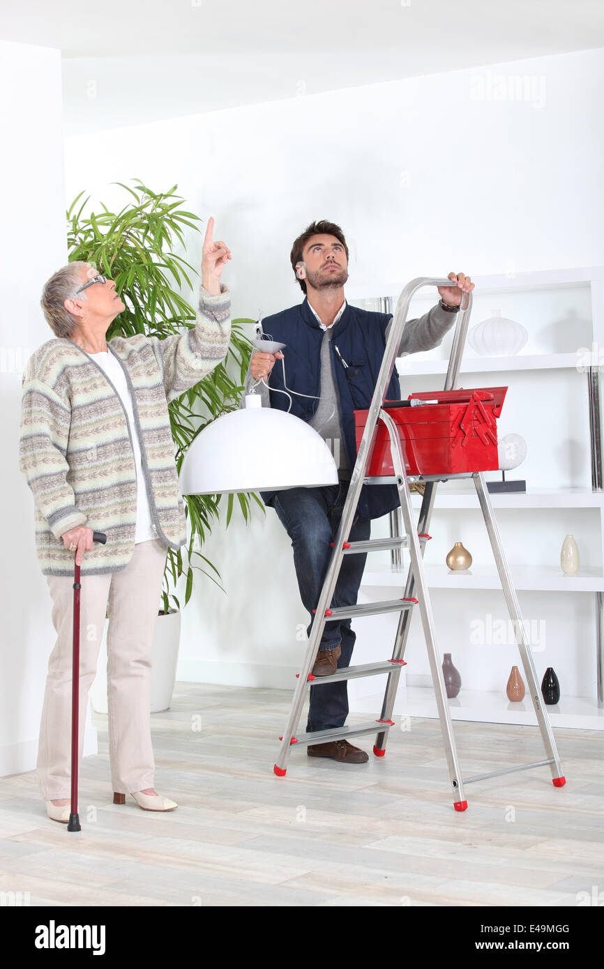 Mann, die passende Deckenleuchte für alte Dame Stockfoto